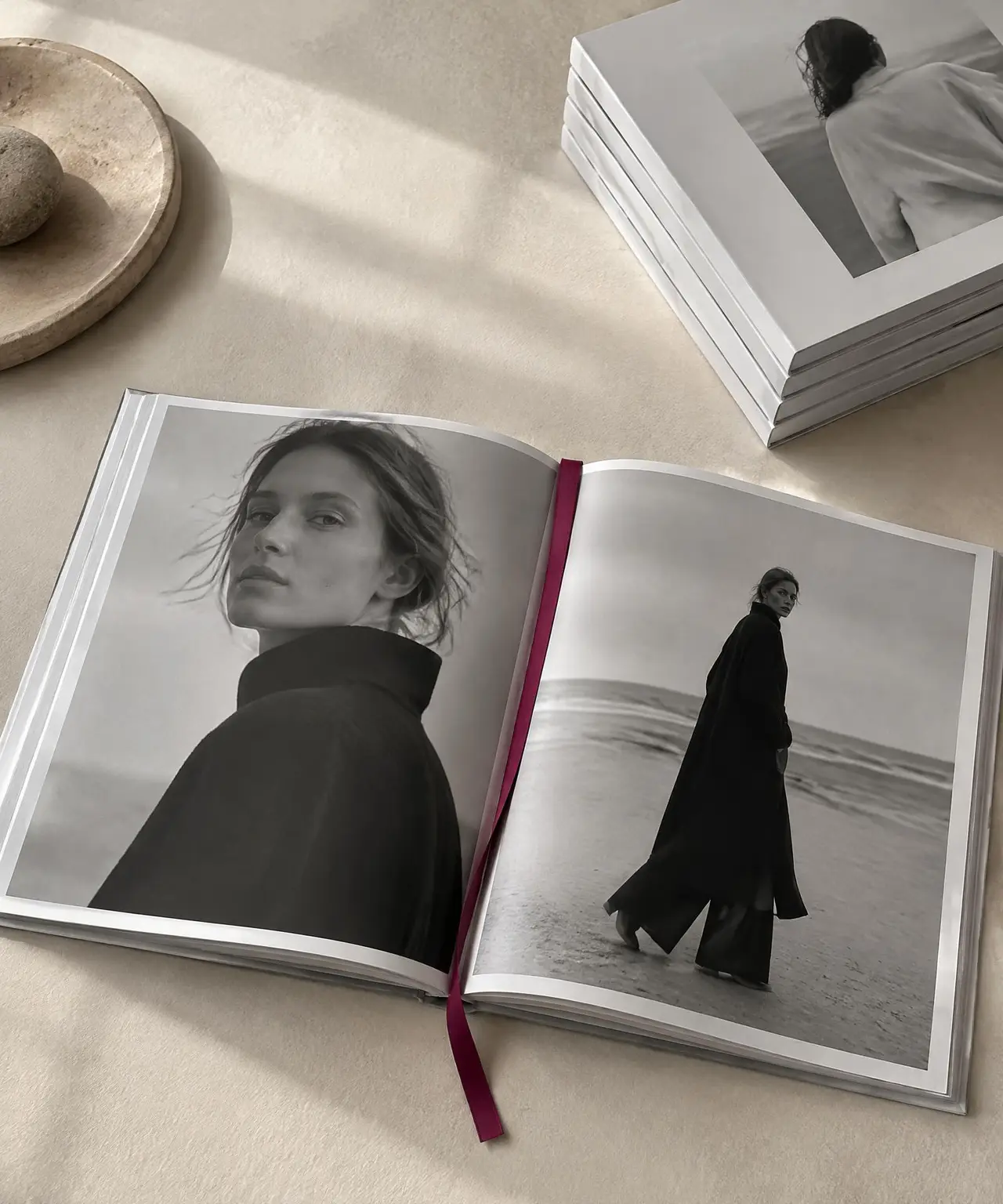 Open lookbook with black and white photography beside a stack of printed books