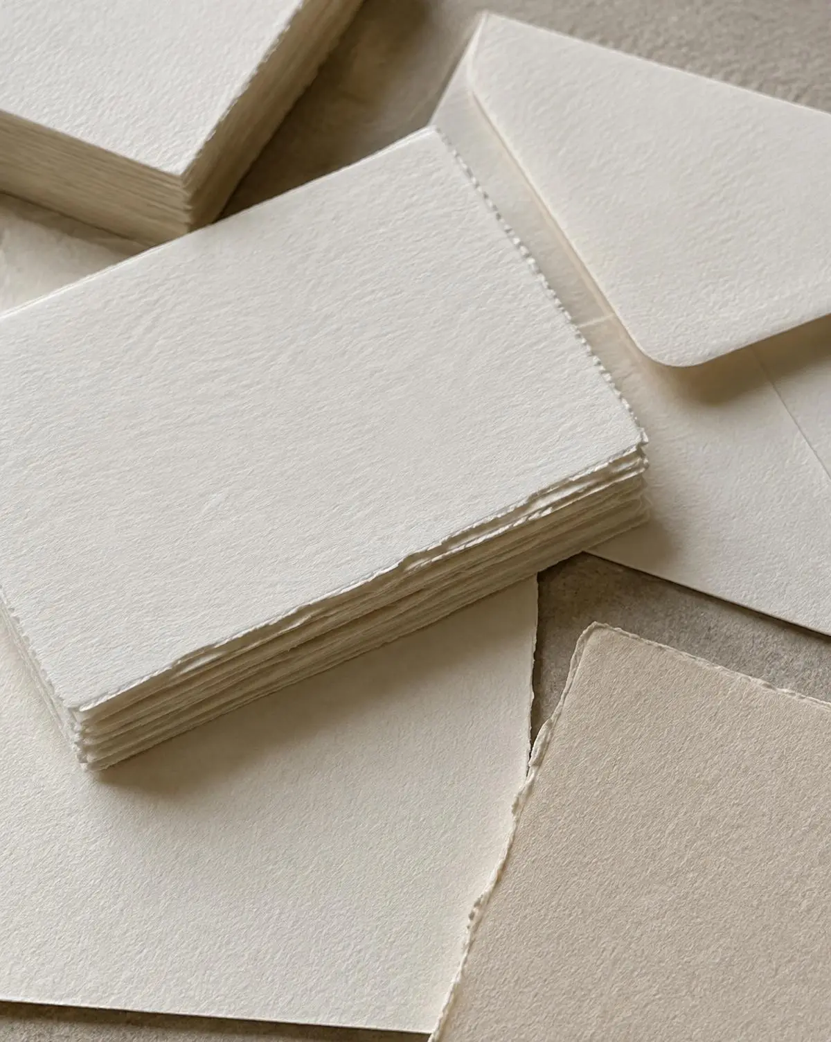Stack of deckle-edged cotton paper cards and envelopes